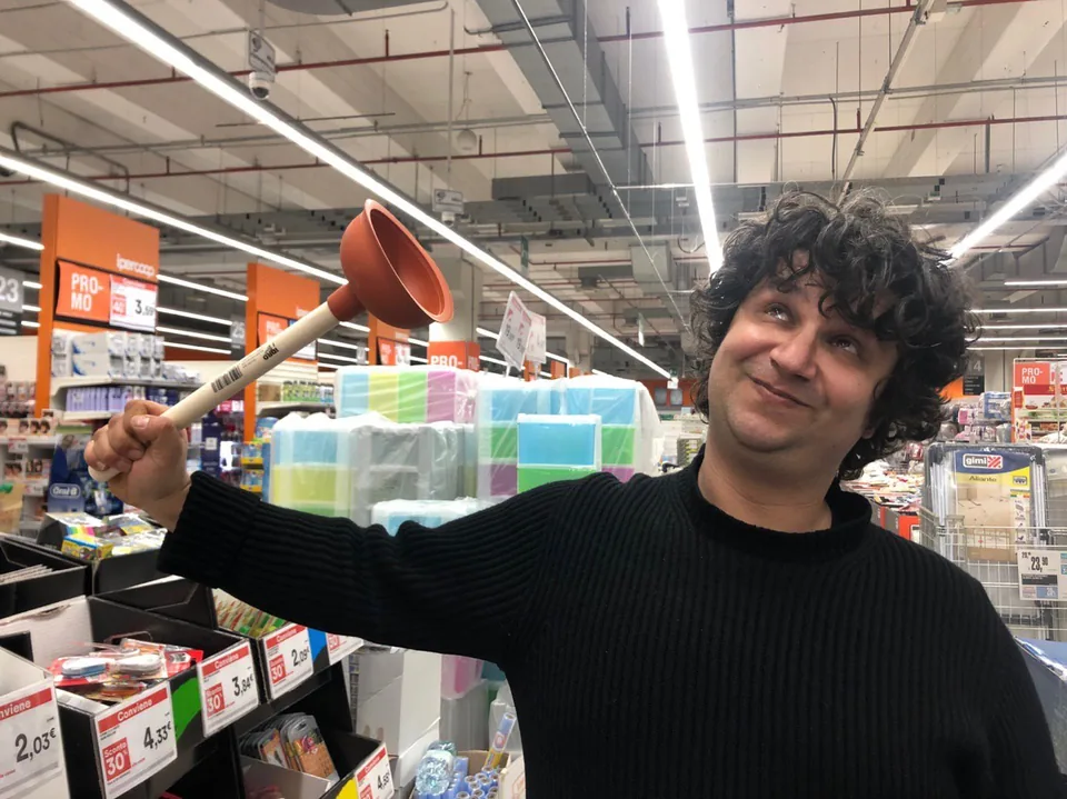 Daniele Lantieri sorride tenendo in mano uno sturalavandini in un negozio